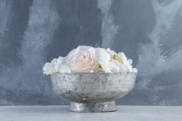 Gratis foto witte rozen in een ijzeren kom, op de witte achtergrond.