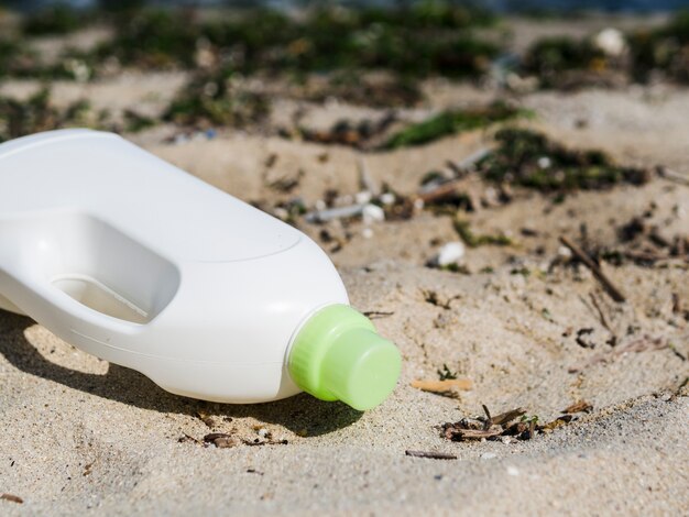 Witte wasmiddelfles op strandzand