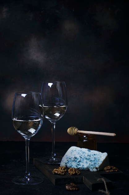 Witte wijn in fijn glas met blauwe kaas, honing, walnoten op donker