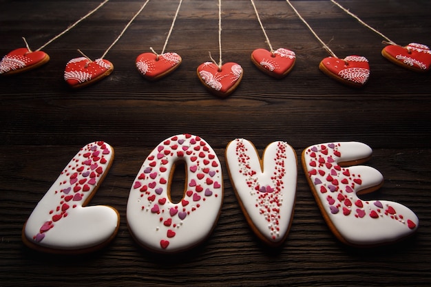 Woord &quot;liefde&quot; gemaakt van cookies met hart-vormige cookies opknoping van kabels op een houten tafel