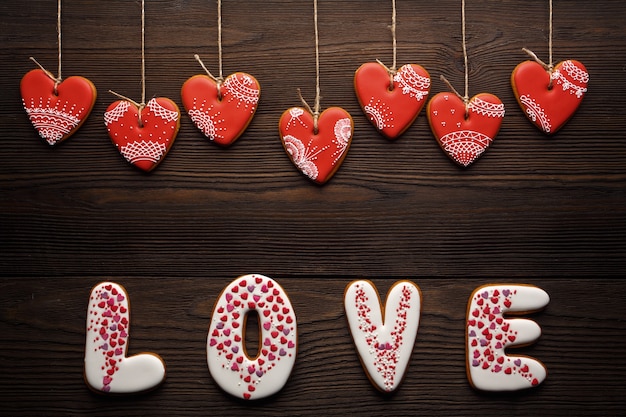 Woord &quot;liefde&quot; gemaakt van cookies met hart-vormige cookies opknoping van kabels op een houten tafel