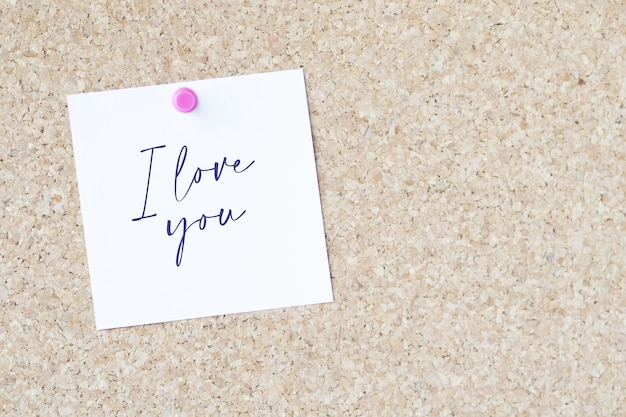 Woorden "I love you" op een papier dat met een speld aan een bord is bevestigd