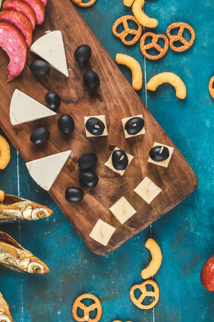 Worst segmenten met kaas blokjes, olijven en crackers met droge vis op de blauwe tafel, bovenaanzicht