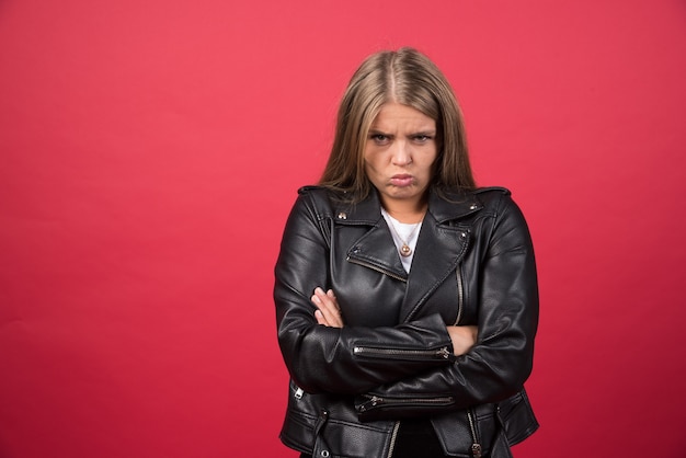 Wrokkige vrouw in leren jas heeft een ongelukkige grimas en kruist haar armen over het lichaam