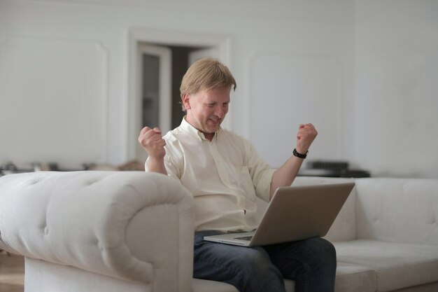 XAman thuis met computer met winnende uitdrukking