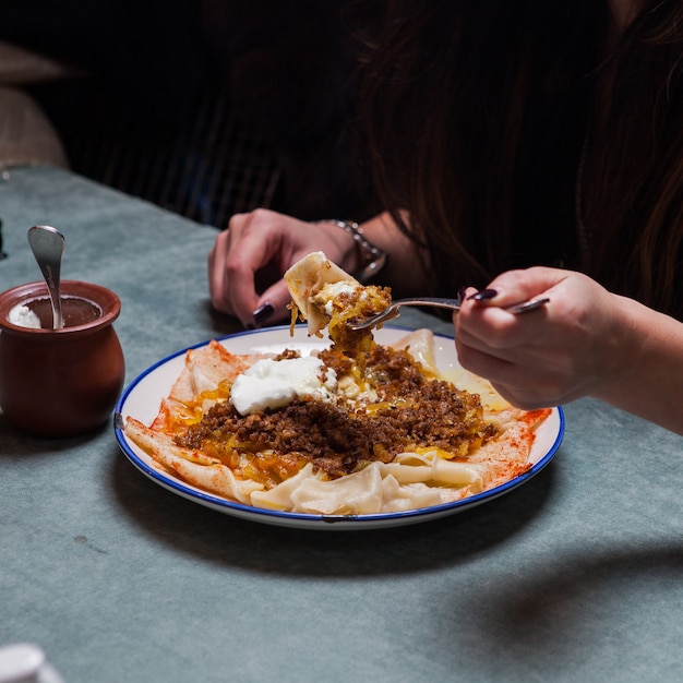 xengel met yoghurt en menselijke hand en vork in ronde plaat