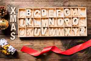 Gratis foto xmas titel in de buurt van letters in het geval, lint en ornament bal