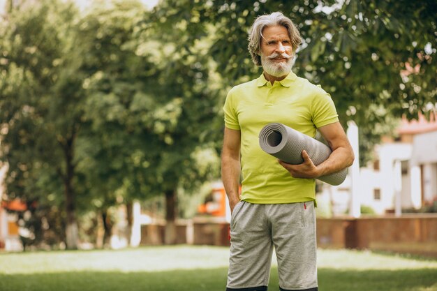 Yoga-instructeur van middelbare leeftijd met mat in park