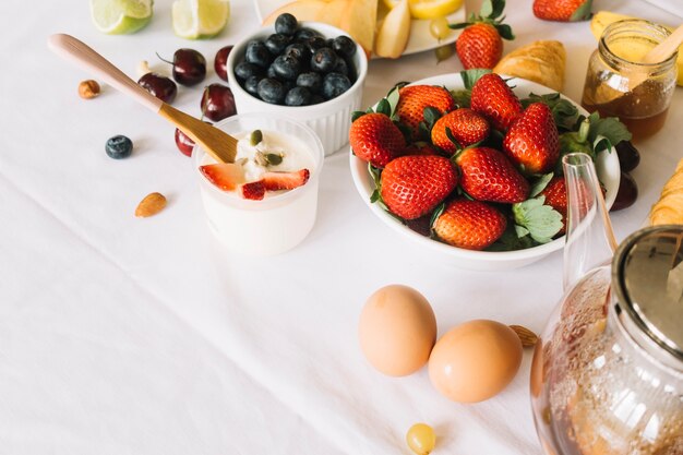 Yoghurt; ei; theepot en fruit op witte achtergrond