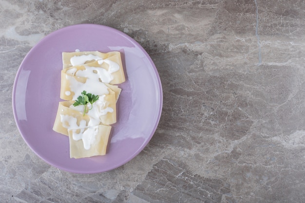 Yoghurt op lasagnebladen met greens op de plaat, op het marmeren oppervlak.