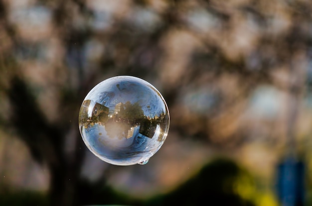 Zachte focus van een zeepbel met weerspiegeling van stadsgebouwen en bomen erop