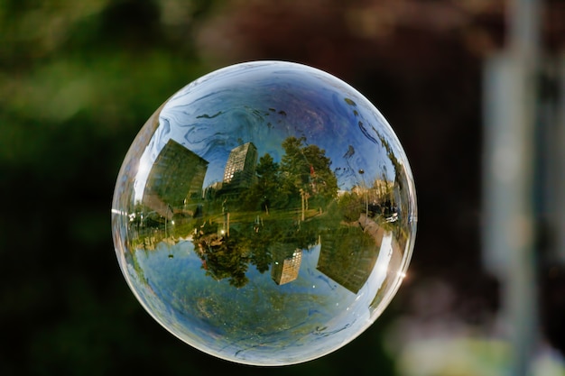 Zachte focus van een zeepbel met weerspiegeling van stadsgebouwen en bomen erop