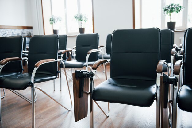 Zakelijk klaslokaal overdag met veel zwarte stoelen. Klaar voor studenten