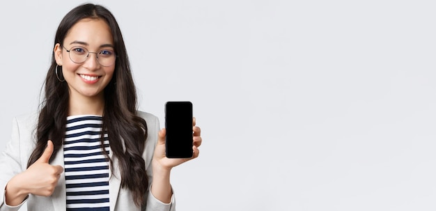 Zakelijke financiën en werkgelegenheid vrouwelijke succesvolle ondernemers concept Close-up van stijlvolle moderne Aziatische zakenvrouw introduceert mobiele applicatie met thumbsup in goedkeuring