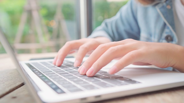 Zakelijke freelance Aziatische vrouw die werkt, projecten doet en e-mail op laptop of computer verzendt terwijl het zitten op lijst in koffie.