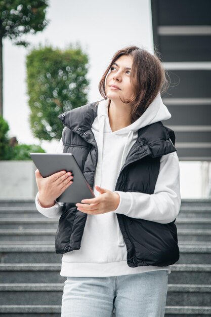 Zakelijke jonge vrouw met een tablet op de achtergrond van het gebouw