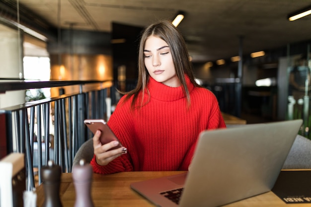 Zakelijke jonge vrouw met laptop en telefoon in café