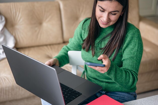 Zakelijke jonge vrouw met smartphone en laptop thuis