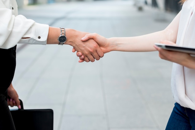 Zakelijke vrouwen hand in hand in de straat