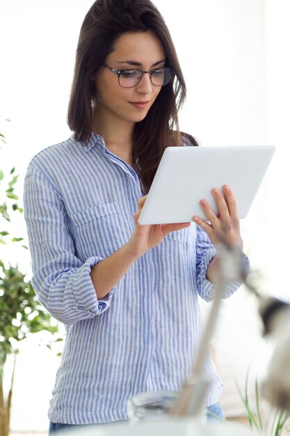 Zaken jonge vrouw met behulp van haar digitale tablet in het kantoor.