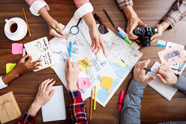 zakenlieden handen op houten tafel met documenten en ontwerpen