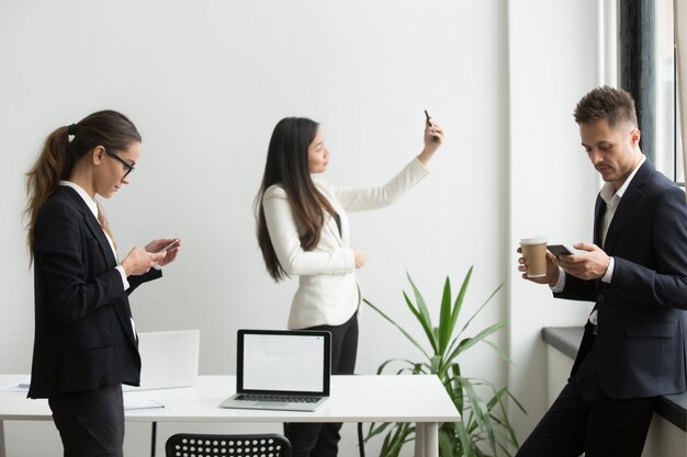 Zakenlui die smartphones gebruiken die, selfie in bureau tijdens onderbreking sms&#39;en texting