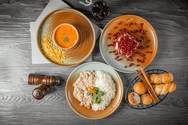 zakenlunch tomado soep met kaas granaatappel salade kip stroganoff met rijst brood drinken en zwarte peper op tafel