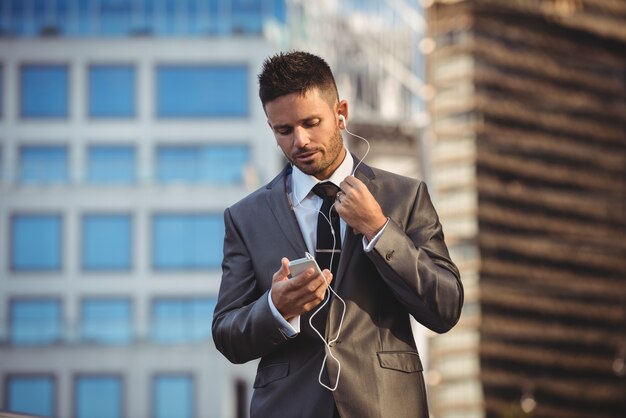 Zakenman die aan muziek op mobiele telefoon luistert