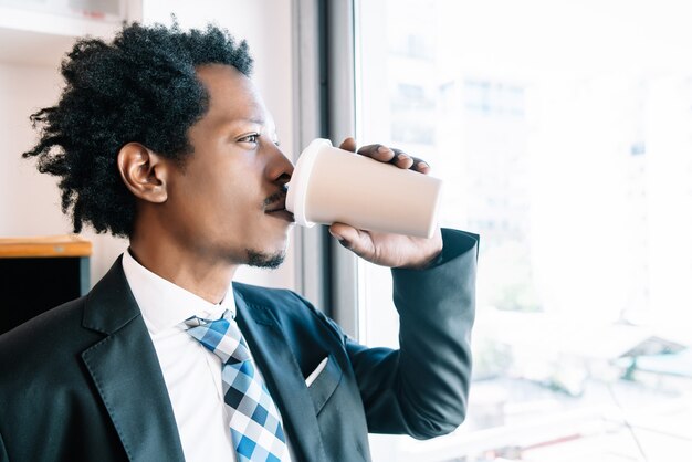 Zakenman die een kopje koffie drinkt terwijl hij een pauze neemt van zijn werk op zijn kantoor. Bedrijfsconcept.