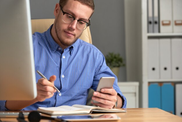 Zakenman die herinneringsapp controleren op de telefoon en het dagboek