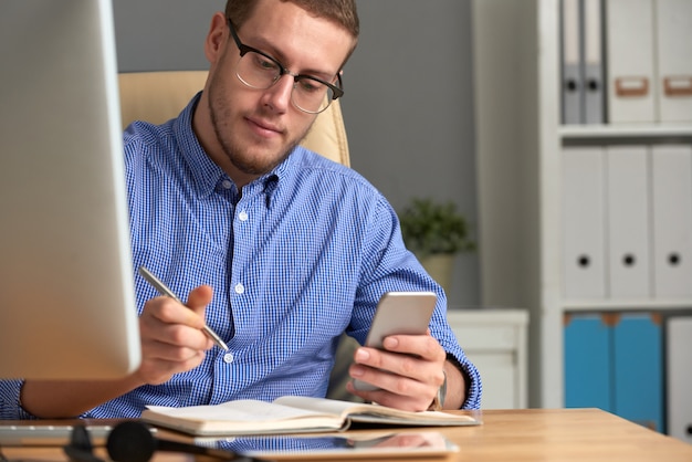 Zakenman die herinneringsapp controleren op de telefoon en het dagboek