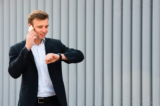 Zakenman die horloge bekijkt terwijl op de telefoon