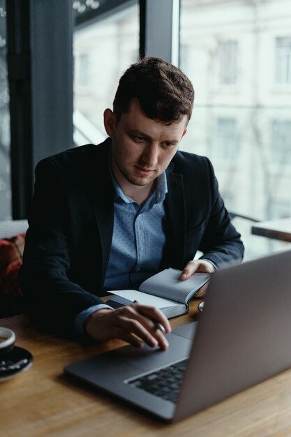 Zakenman die laptop met behulp van terwijl het zitten bij de houten lijst