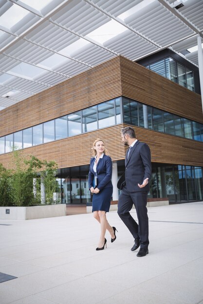 Zakenman die met collega buiten de bureaubouw lopen