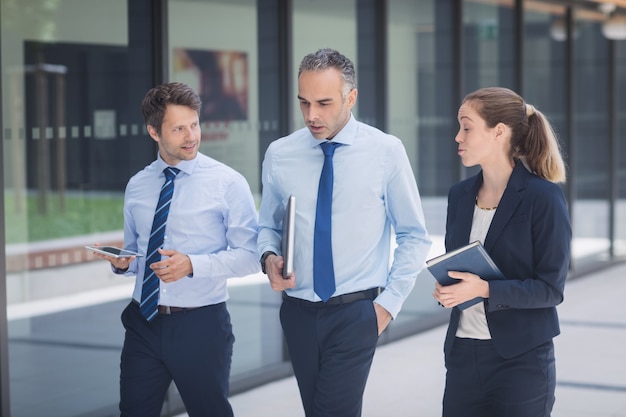 Zakenman die met collega's buiten de bureaubouw lopen