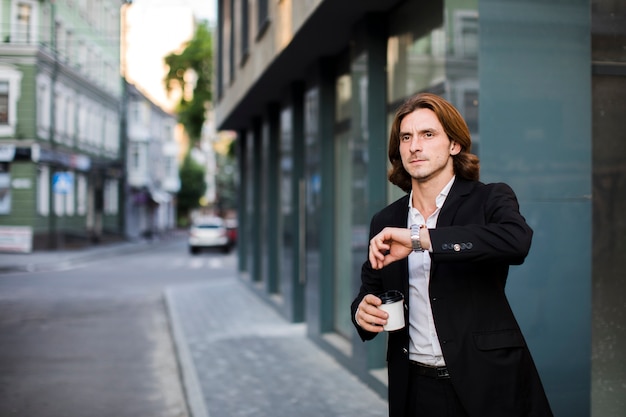 Zakenman die met koffie zijn horloge bekijkt