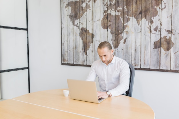 Gratis foto zakenman die met laptop in bureau werkt