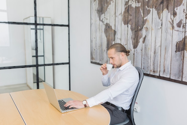 Zakenman die met laptop in bureau werkt