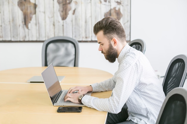 Zakenman die met laptop in bureau werkt