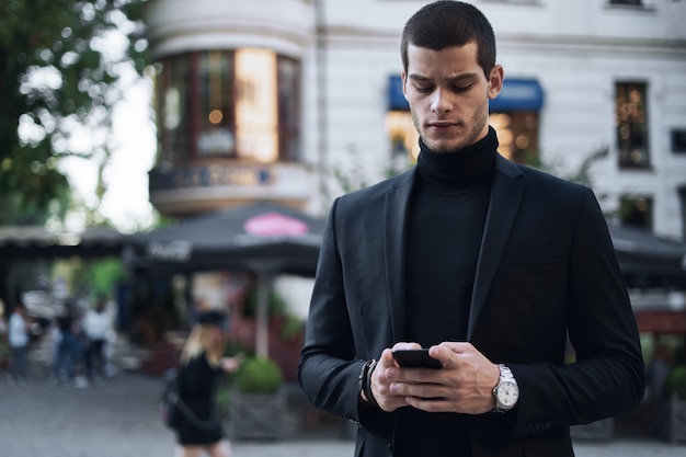 Zakenman die mobiele telefoon houdt en het in openlucht bekijkt