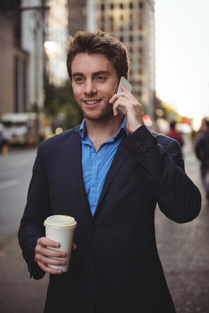 Zakenman die op mobiele telefoon spreekt en koffie houdt