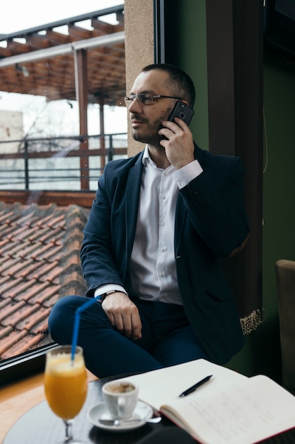 Zakenman die op telefoon in koffie spreekt