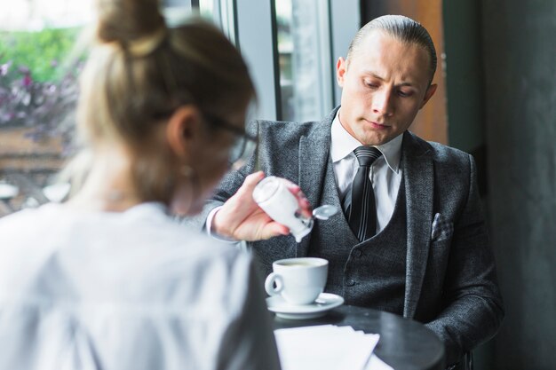 Zakenman die suiker in koffie toevoegt