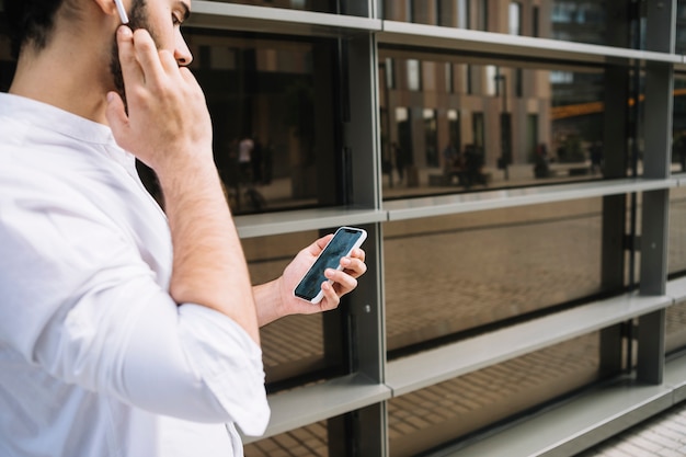 Gratis foto zakenman die videoconferentie op smartphone doen en met bluetooth handsfree apparaat spreken