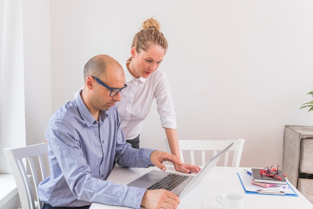 Zakenman en onderneemster die laptop bekijken