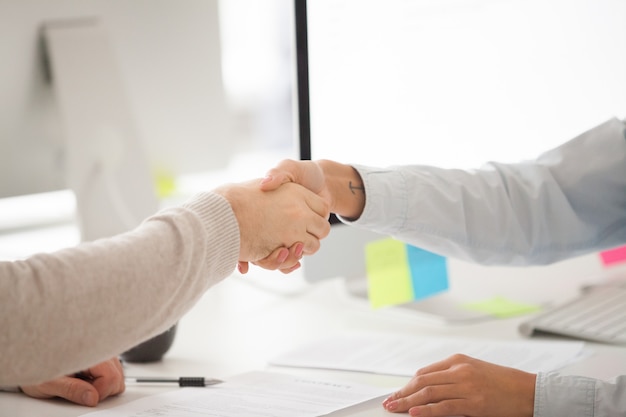 Zakenman en zakenvrouw handshaking na ondertekening van het contract of succesvolle onderhandeling