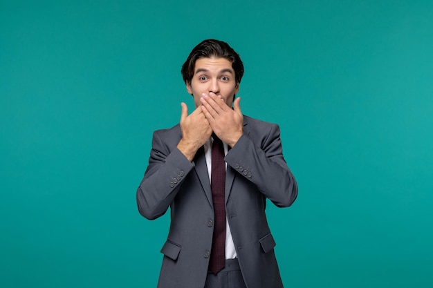 Zakenman knappe jonge brunette man in grijs kantoor pak en stropdas met stilte gebaar