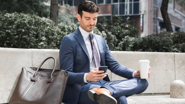 Zakenman met drankje met behulp van smartphone