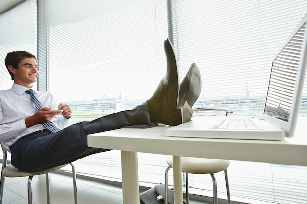 Zakenman met zijn voeten op de computer bureau