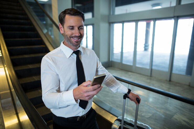 Gratis Foto zakenman op roltrap met behulp van mobiele telefoon